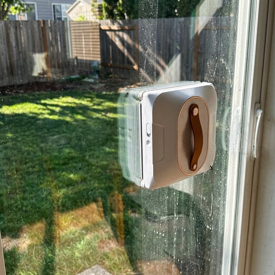 A patio door half-cleaned by the robot — clear glass on one side, dust on the other